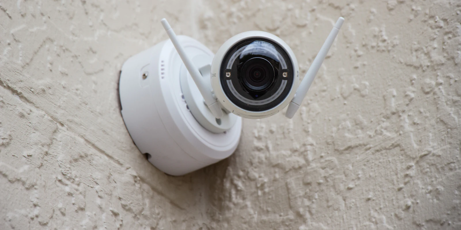 White outdoor security camera mounted on a textured wall